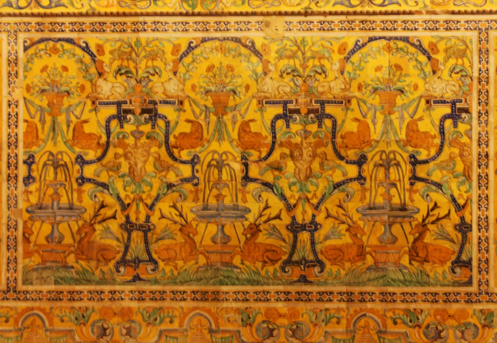 Eine Wand aus goldgelben Azulejos mit einem sich wiederholenden Muster aus Vasen und Blattwerk