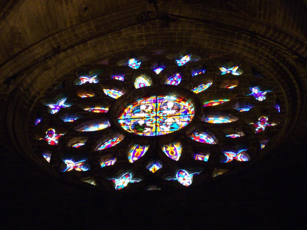 Ein Rosettenfenster aus Buntglas in der Kathedrale von Sevilla, von außen beleuchtet