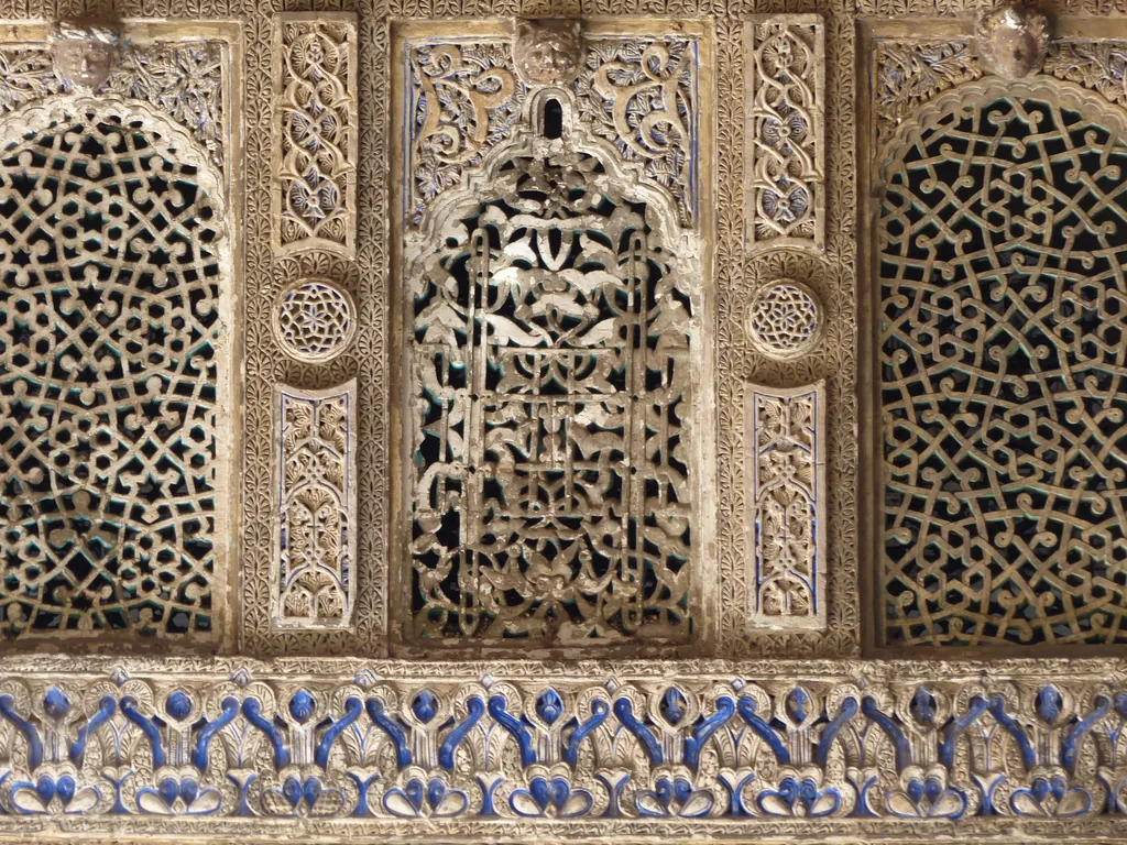 Geschnitzte Stucktafel über einem Band blau-weißer Azulejos im Patio de las Doncellas