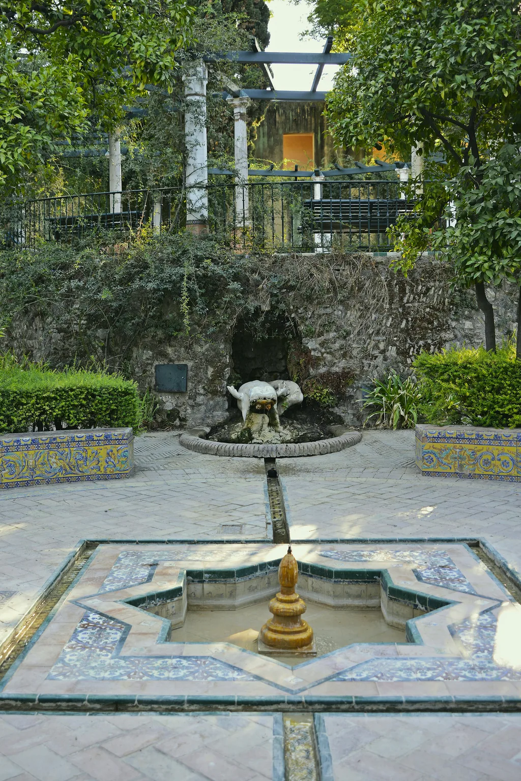 Ein flacher Brunnen, mit gemusterten Azulejos ausgekleidet, in den Alcázar-Gärten