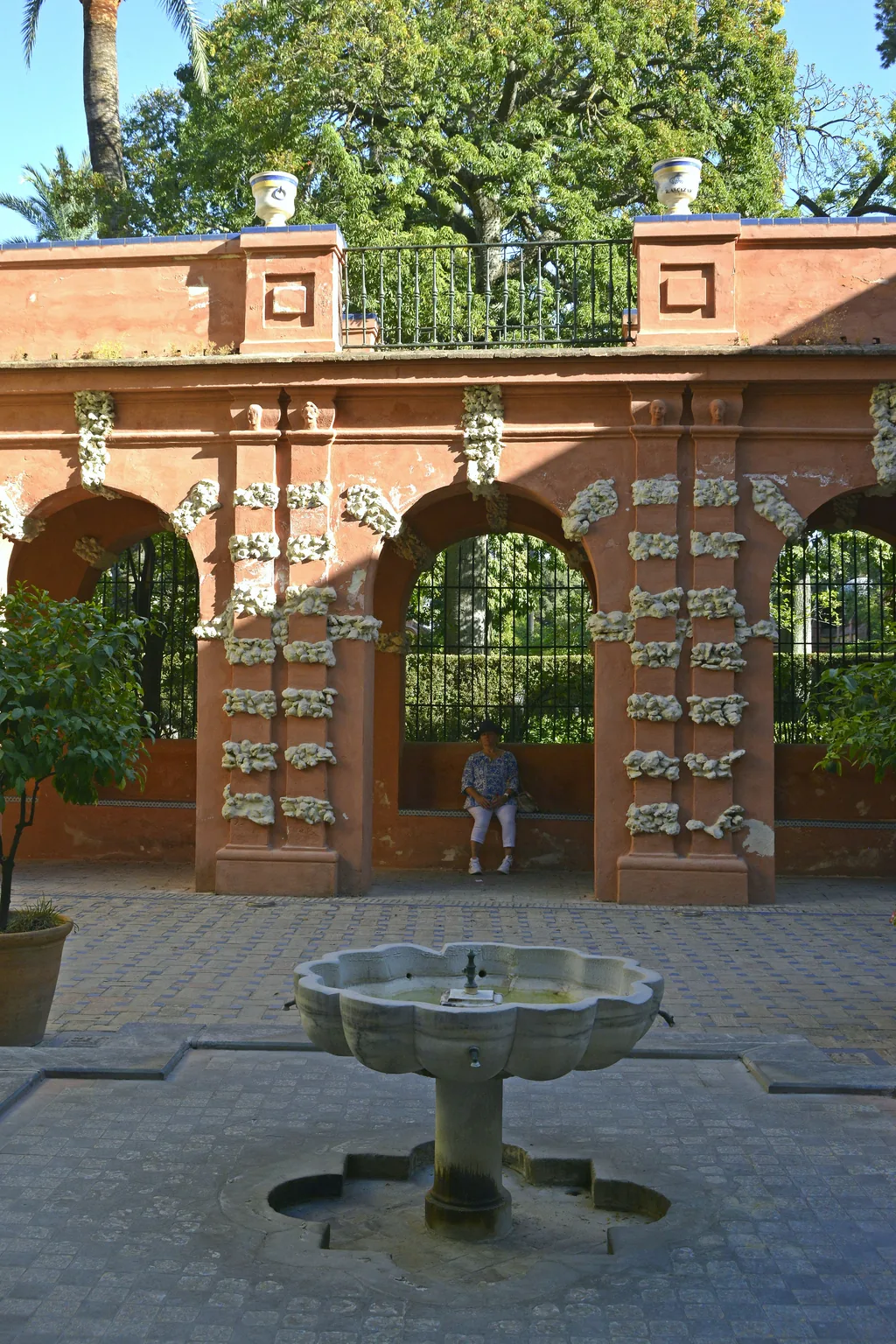 Backsteinbögen und ein kleiner Brunnen in einem ummauerten Abschnitt der Alcázar-Gärten