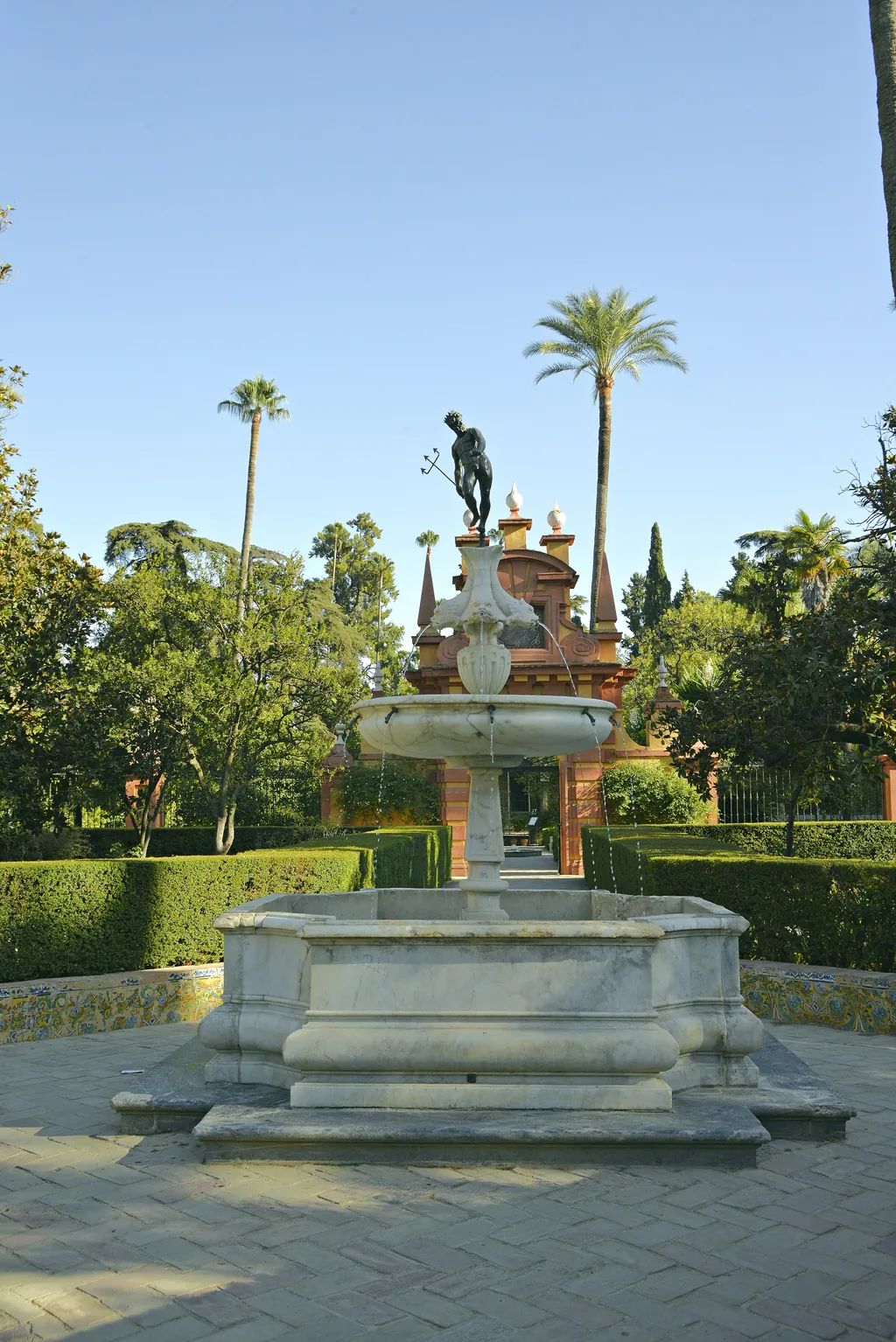 Ein Steinbrunnen mit einer Bronzefigur als Bekrönung in den Gärten des Alcázar