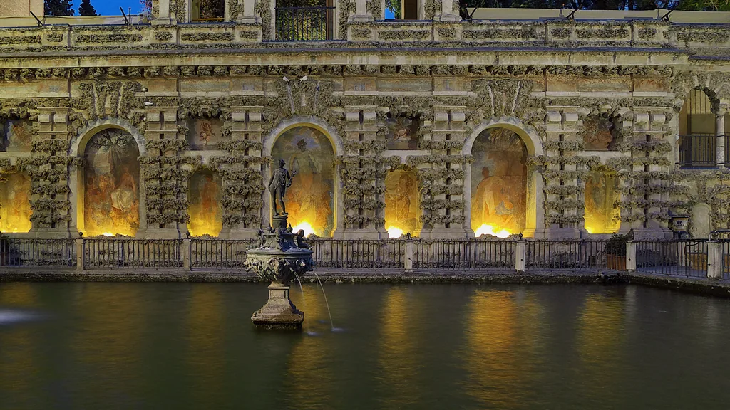 Der Estanque de Mercurio bei Nacht beleuchtet, die Fassade spiegelt sich im dunklen Wasser