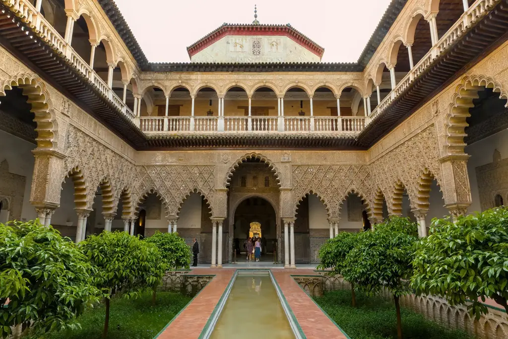 Der Patio de las Doncellas entlang seines Mittelbeckens, mit Orangenbäumen in den abgesenkten Beeten und geschnitzten Mudéjar-Bögen auf beiden Seiten