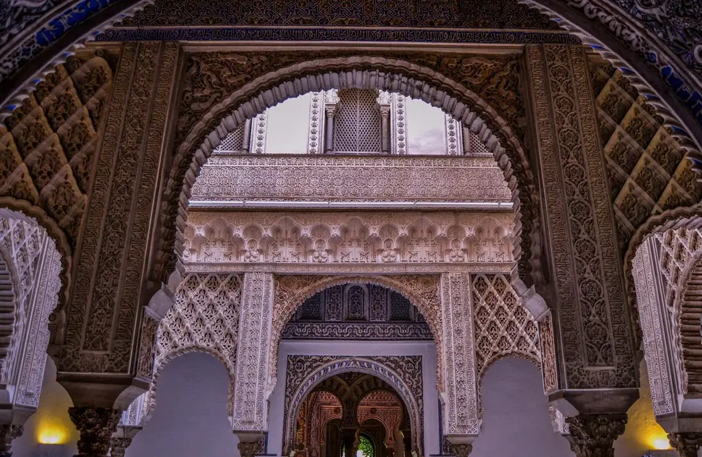 El Patio de las Muñecas visto a través de los arcos del Salón de Embajadores, con columnas y yeserías hacia las estancias privadas